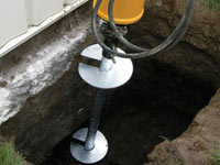 Installing a helical pier system in the earth around a foundation in Sterling