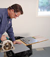 installing a waterproof vapor barrier on a basement floor to prepare for basement carpeting in a Sterling home